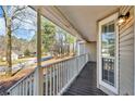 Covered porch with wooden deck and white railing with a view of the neighborhood street at 50 Riverside Ct, Hampton, GA 30228