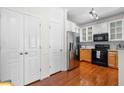 Kitchen area with stainless refrigerator, hardwood flooring, and white cabinetry with glass accents at 375 Highland Ne Ave # 908, Atlanta, GA 30312