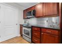 Kitchen with stainless steel appliances, cherry wood cabinets, and black countertops at 390 17Th Nw St # 1063, Atlanta, GA 30363