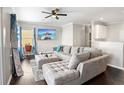 Bright living room with hardwood floors, comfortable gray sofa, ceiling fan, and a view to the kitchen at 5227 Whiteoak Se Ave, Smyrna, GA 30080