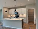 Bright kitchen with white cabinets, island, stainless appliances and open pantry, offering ample storage at 115 Laurel Farms Ln, Dallas, GA 30157