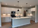 Modern kitchen features white cabinets, stainless steel appliances, and an island with pendant lighting at 115 Laurel Farms Ln, Dallas, GA 30157