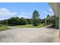 Large concrete driveway next to covered porch overlooking a picturesque yard with mature trees and greenery at 410 Bowen Ne Rd, White, GA 30184