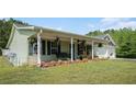 Inviting front porch featuring a swing, rocking chairs, potted plants, and views of the surrounding landscape at 410 Bowen Ne Rd, White, GA 30184