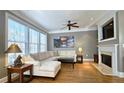 Comfortable living room featuring hardwood floors, fireplace, large windows, and a ceiling fan at 3699 Ashford Creek Ne Hl, Atlanta, GA 30319