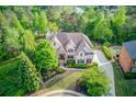Stunning aerial perspective of an elegant home surrounded by mature trees and a beautifully landscaped yard at 2400 Weber Heights Way, Buford, GA 30519