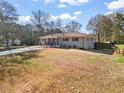 Exterior view of a charming single-story home with a large front yard and a mix of mature trees and open space at 4493 Old Hiram Lithia Spgs Rd, Powder Springs, GA 30127