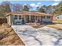 Inviting single-story home with a fresh driveway, manicured lawn, and a delightful front porch seating area at 4493 Old Hiram Lithia Spgs Rd, Powder Springs, GA 30127