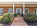 Close-up of brick home's entryway featuring a wood front door and brick stairs surrounded by lush greenery at 320 Morganshire Pl, Atlanta, GA 30350