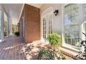 Covered porch with brick floor and white columns, offering a view of the home's exterior and garden at 320 Morganshire Pl, Atlanta, GA 30350