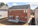 Back exterior showcasing a brick facade, a small patio, and a well-manicured lawn at 5819 Rue Chase Way, Tucker, GA 30084