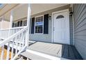Inviting front porch featuring a white door with sidelights, gray wood floors, and white railings at 195 W Fork Way, Temple, GA 30179