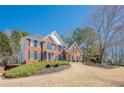 Charming two-story red brick home with black shutters and a well-manicured lawn and landscaped front yard at 4780 Woodruff Trce, Cumming, GA 30028