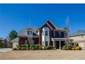 Charming brick two-story home featuring a manicured lawn, mature landscaping, and a welcoming front porch at 2480 Copper Mill Trl, Cumming, GA 30041