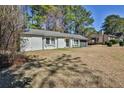 View of a single-story home with a dark garage door, and a lush green lawn, trees in the background at 3915 Basil Sw Way, Atlanta, GA 30331