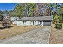 Charming single-story house with a long driveway leading to the garage and a well-maintained yard at 3915 Basil Sw Way, Atlanta, GA 30331