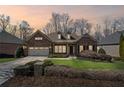 Dusk view of a charming brick home with well-manicured lawn, complimented by a two-car garage and mature trees at 4930 Cecilia Sq, Cumming, GA 30040