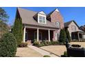 Beautiful brick home with a well-kept lawn, lush greenery, and front porch with seating area at 184 Cadence Trl, Canton, GA 30115