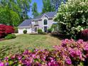 Elegant two-story house boasts vibrant azaleas, manicured lawn, and a symmetrical facade, creating a picturesque curb appeal at 3304 Woolbridge Ct, Marietta, GA 30062
