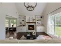 Bright living room features a stone fireplace, built-in shelving, dark hardwood floors and a modern chandelier at 5570 Rolling Oaks Dr, Cumming, GA 30040