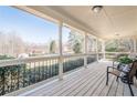 Inviting covered porch with wood floors, black railings and wooded view provides a relaxing outdoor space at 6365 Mountain View Trl, Cumming, GA 30041