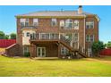 Two-story brick home with a wooden deck, stairs, and a grassy backyard at 8056 Revere Dr, Mcdonough, GA 30252