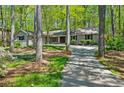 Single story home with a long driveway surrounded by mature trees and landscaping at 1959 Grand Prix Ne Dr, Atlanta, GA 30345