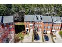 Aerial view showcases brick townhomes with garages, driveways, and lush green surroundings at 5589 Trace Views Dr, Norcross, GA 30071