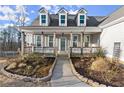 Close-up of a charming front porch with decorative columns and manicured flower beds at 411 Spring Lake Hls, White, GA 30184