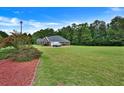 Expansive lush green backyard with mature trees, a well manicured lawn, and a glimpse of the brick home at 501 Barhams Ridge Dr, Mcdonough, GA 30252