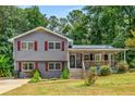 Inviting two-story home with a covered porch, gray siding, and red shutters in a wooded setting at 3989 Woodland Se Cir, Conyers, GA 30013
