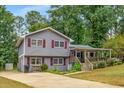 Gray two-story home with red shutters, concrete driveway, and a charming covered front porch at 3989 Woodland Se Cir, Conyers, GA 30013