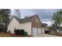 Side view of the home features brick and siding, manicured lawn, and two-car garage at 1956 Cutters Mill Way, Lithonia, GA 30058