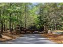 Beautiful, custom wood driveway gate surrounded by dense trees at 938 Crescent River Pass, Suwanee, GA 30024