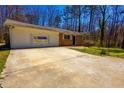 Exterior view of ranch-style home, showcasing the attached garage and spacious driveway at 8684 Chestnut Ln, Lithia Springs, GA 30122