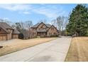 Spacious two-story brick home with long driveway and well-manicured lawn and landscaping at 6350 Old Wood Hollow Way, Buford, GA 30518