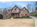 Charming two-story brick home with manicured landscaping and a welcoming covered front porch at 6350 Old Wood Hollow Way, Buford, GA 30518