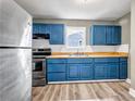 Stylish kitchen featuring stainless steel appliances, bright blue cabinets, and hardwood floors at 225 Joe Louis Nw Dr, Atlanta, GA 30314