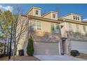 View of a tan townhome featuring brick accents, a two-car garage, and a welcoming entryway at 426 Mulberry Se Row, Atlanta, GA 30354