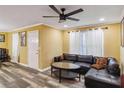 A sunlit living area has stylish floors, a sectional sofa, bright yellow walls, and a modern ceiling fan at 660 Simmons St, Atlanta, GA 30318