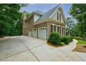 Spacious three-car garage with an expansive driveway, set against a backdrop of lush greenery at 5053 Chapel Xing, Douglasville, GA 30135