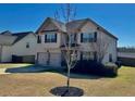 Two-story home featuring a well-maintained lawn, tree, and driveway with an attached two-car garage at 611 Winners Cir, Locust Grove, GA 30248