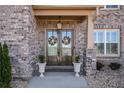 Charming brick home entrance with a double door, decorative wreaths, and manicured landscaping at 1604 Falcon Ct, Locust Grove, GA 30248