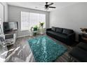 Bright living room featuring hardwood floors, a dark sofa, and a large window with natural light at 217 Odyssey Turn Nw, Conyers, GA 30012