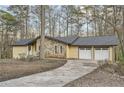 Home featuring stone facade, light yellow siding, attached two-car garage and long driveway at 4716 Habersham Sw Rdg, Lilburn, GA 30047