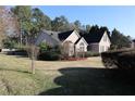 A view of a two-story home with brick exterior and a well-manicured lawn surrounded by trees at 1313 Idlewood Ct, Mcdonough, GA 30252