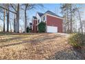 View of the side of a well-maintained two-story brick home featuring an attached garage and a paved driveway at 2118 Sableshire Se Way, Conyers, GA 30013