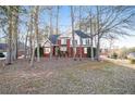 A two-story brick home with a well-manicured front lawn, mature trees, and classic architectural details at 2118 Sableshire Se Way, Conyers, GA 30013