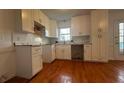 Well-lit kitchen featuring wooden floors, white cabinets, a sink, and tile backsplash at 3052 Glynn Mill Dr, Snellville, GA 30039