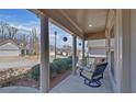 Cozy covered front porch with decorative columns, a comfortable glider, and serene neighborhood views at 5719 Sierra Bend Way, Hoschton, GA 30548